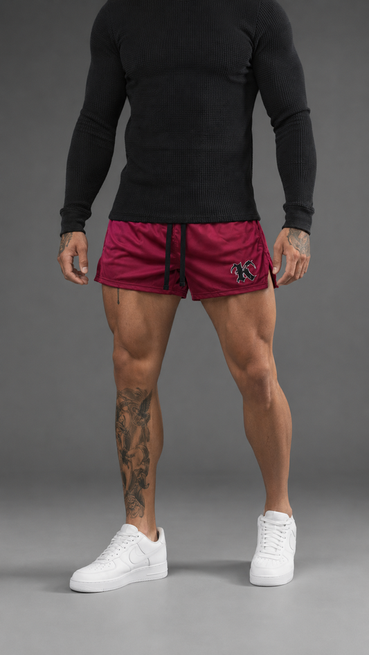 Man wearing Dark red athletic shorts with black drawstrings and a black and silver “K” logo on the right side