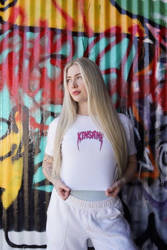 Girl wearing white crop top T-shirt with pink heavy metal lettering reading “KINSANE”