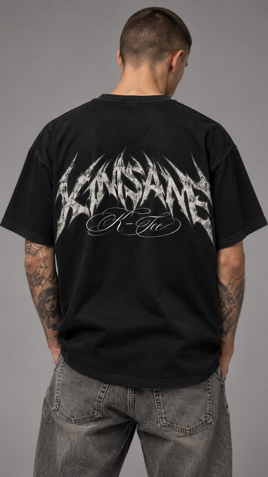 Back view of a man wearing a black t shirt with the gray lettering reading “KINSANE” and white cursive text reading “K-TEC”