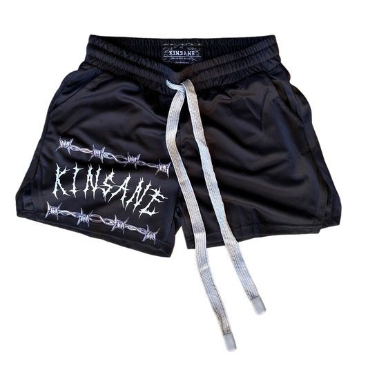 Black athletic shorts with elastic waistband and grey drawstrings with white tribal lettering reading “KINSANE” surrounded by barbed wire on the right leg