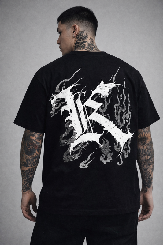 Back view of a man wearing a black T-shirt with a white logo displaying white Japanese style flames and a white letter “K” and various Japanese text