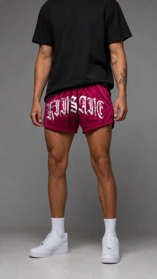 Man wearing Red athletic shorts with black drawstrings with white text across the front reading “KINSANE”