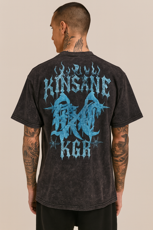Back view of a man wearing a black acid washed t-shirt with light blue logo with flames and barbed wire and lettering reading “KINSANE KGR”