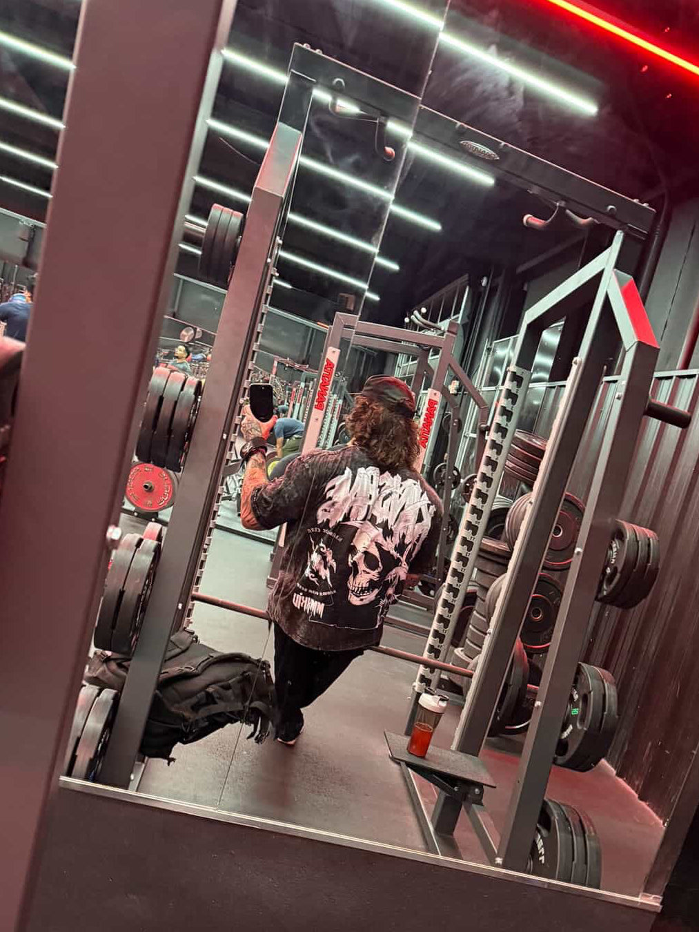 Back view of a man wearing a black acid washed t-shirt with a skull design and white lettering reading “KINSANE” and “KINSANE CLAN KNOWN GRIM REAPERS”