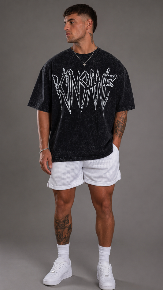 Man wearing Black acid washed t shirt with white outlined text reading “KINSANE”
