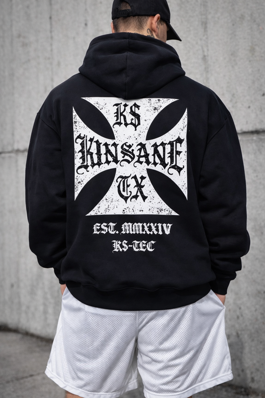 Back view of a man wearing a black hoodie with a white logo with black lettering reading “KINSANE, K$, TX” and white text reading “EST. MMXXIV, K$-TEC”