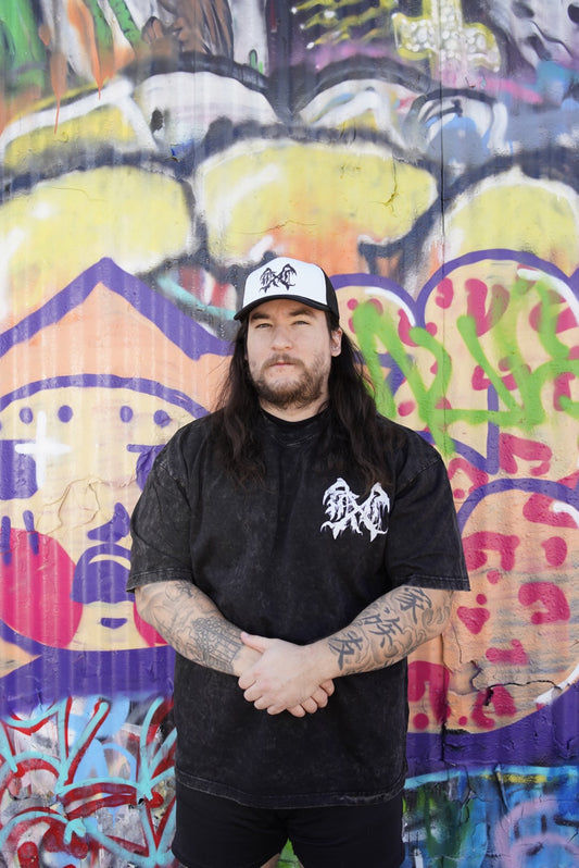 Man wearing Mesh trucker hat with white front panel with a black logo in the middle