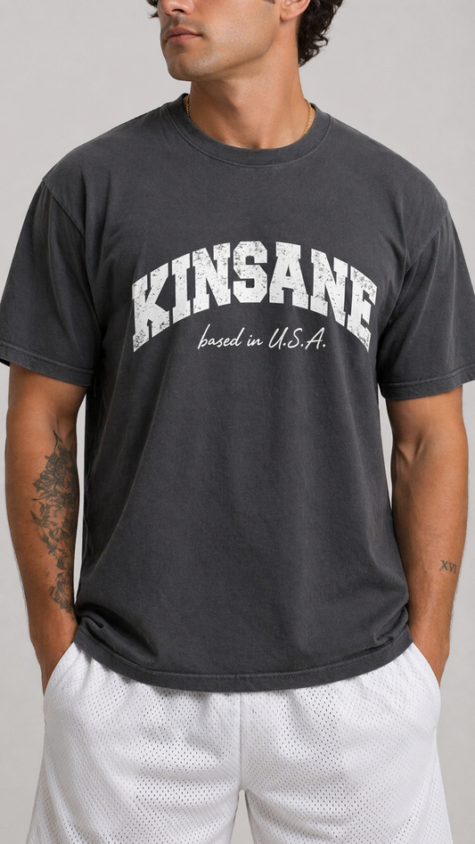 Man wearing Grey t shirt with white text on the front reading “KINSANE BASED IN USA”