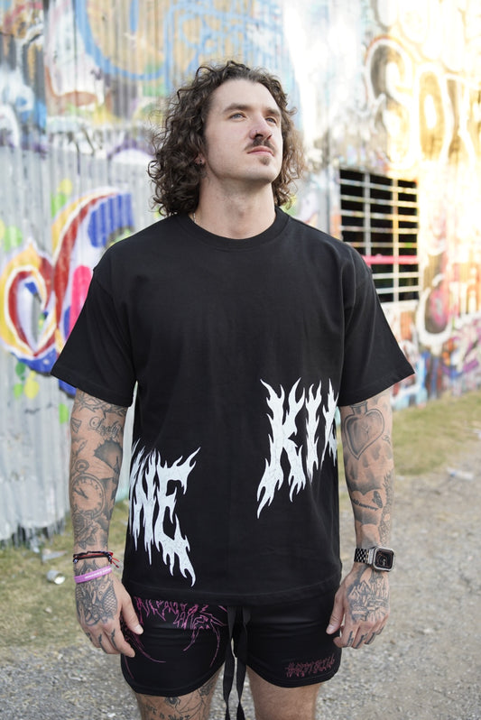 Man wearing a Black T-shirt with white flamed lettering on the sides reading “KIN” and “SANE”