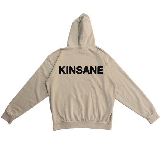 Back view of a beige hoodie with black text reading “KINSANE”