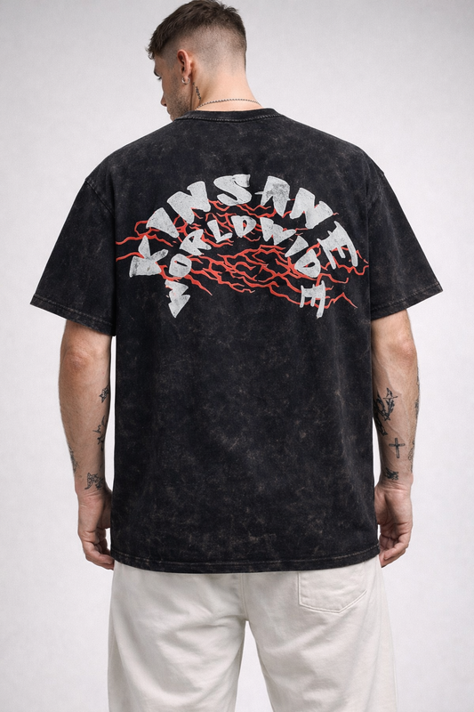 Back view of a man wearing a black acid washed t shirt with red lightning behind white text reading “KINSANE WORLDWIDE”