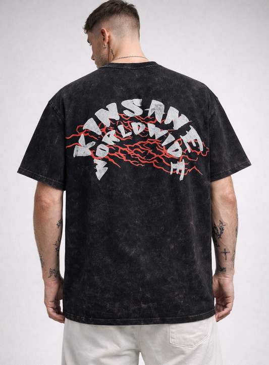 Back view of a man wearing a black acid washed t shirt with red lightning behind white text reading “KINSANE WORLDWIDE”