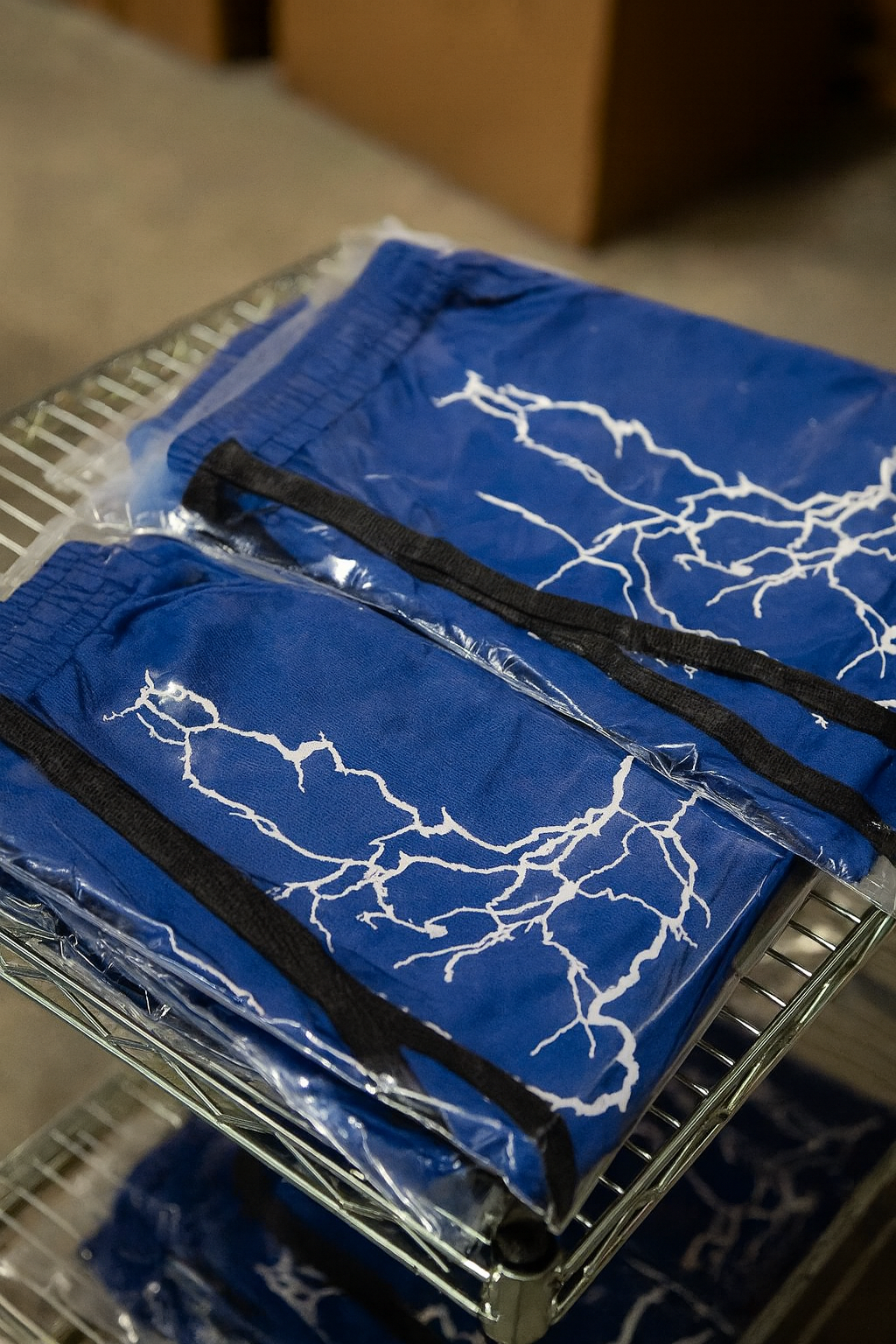 stack of navy blue athletic shorts in merchandise clear bags with lightning designs on the shorts 