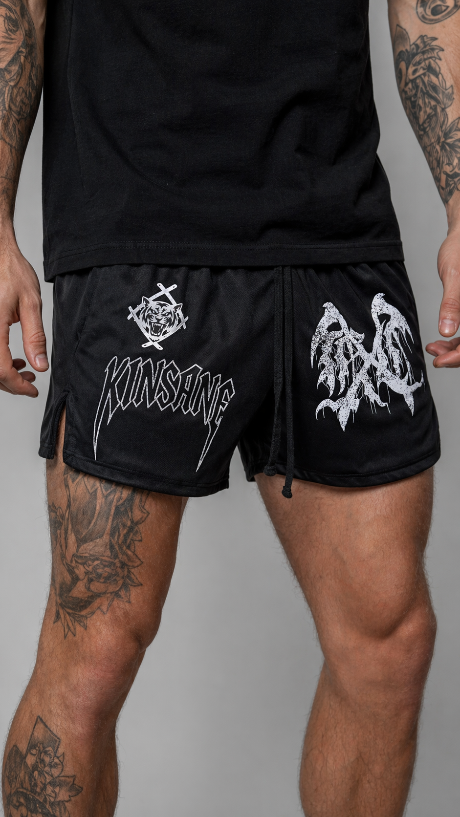 Man wearing Black athletic shorts with black drawstrings and a white tiger logo and white lettering reading “KINSANE” on the right leg and a white logo on the left leg