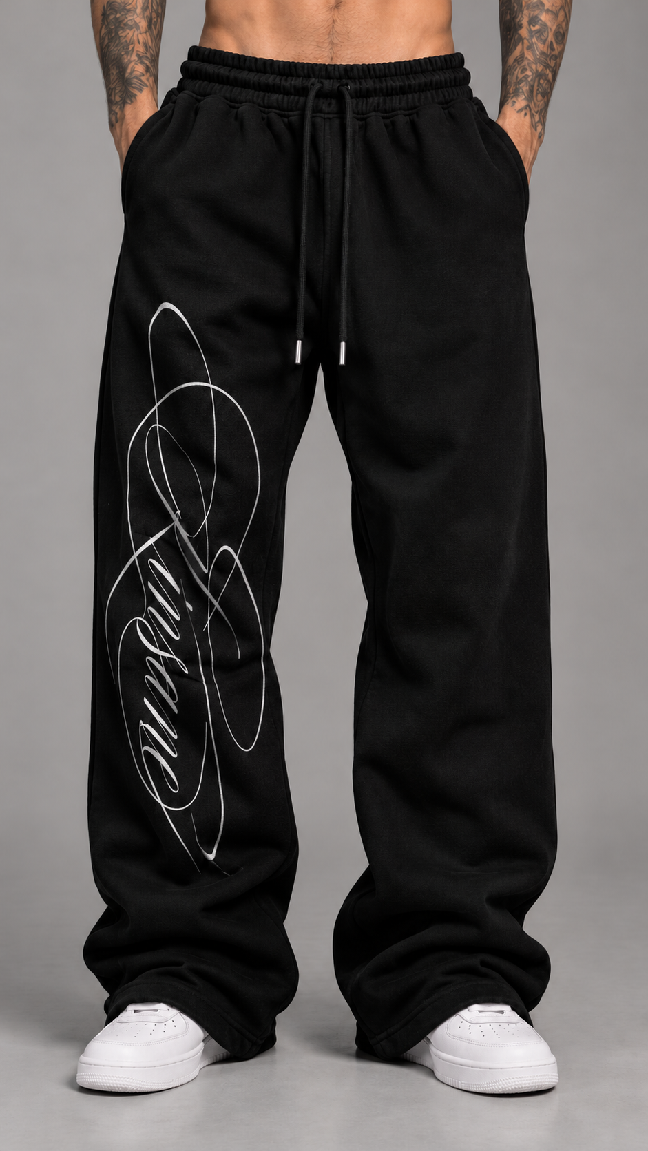 Man wearing Black stacked sweatpants with white printed cursive font reading “Kinsane” on the left side 
