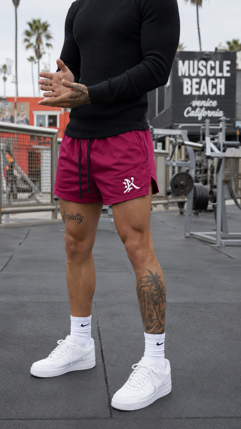 Guy wearing Maroon athletic shorts with black drawstrings and a white logo of the letter “K” on the left leg 