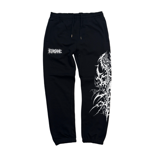 Black cuffed joggers with white chaotic lettering reading “KINSANE” on the left side and white tribal designs on the right side leg