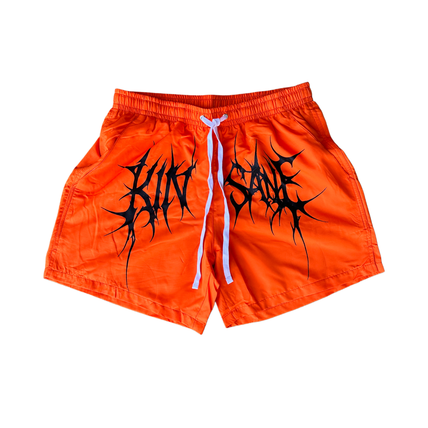 Orange trunks with white drawstrings and black tribal lettering across the middle reading “KINSANE” 