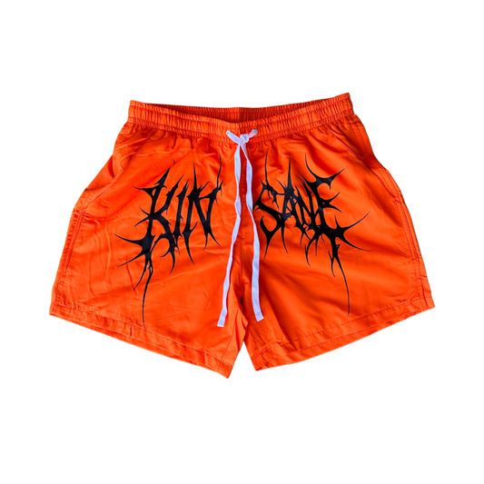 Orange trunks with white drawstrings and black tribal lettering across the middle reading “KINSANE” 