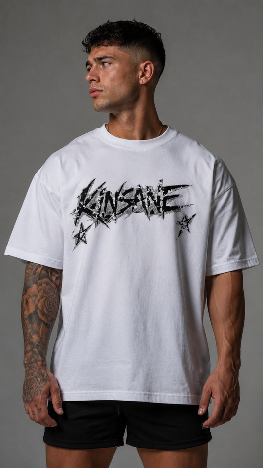 Man wearing White t shirt with black and silver text with stars reading “KINSANE” 