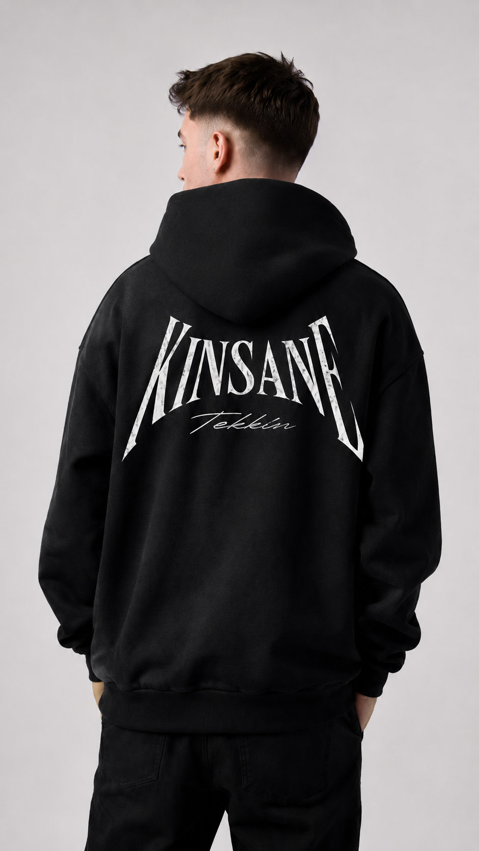 Back view of a man wearing a black hoodie with white text reading “KINSANE TEKKIN” 