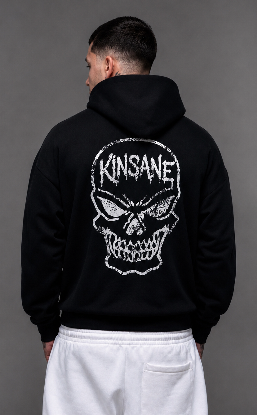 Back view of a man wearing a black hoodie with a white skull design and white text reading “KINSANE” 