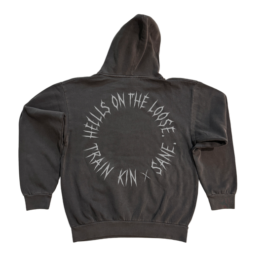 Back view of a dark grey hoodie with silver text in a circle reading “HELLLS ON THE LOOSE. TRAIN KIN X SANE” 