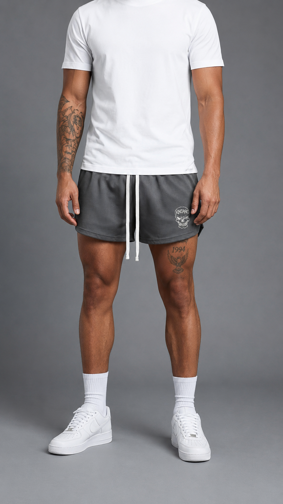 Man wearing Gray athletic shorts with white drawstrings and a white skull logo with white text reading “KINSANE” on the right side 