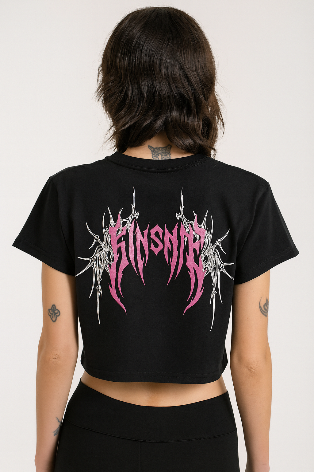 Back view of a girl wearing a black crop top T-shirt with girl tribal lettering reading “KINSANE” and white tribal designs 