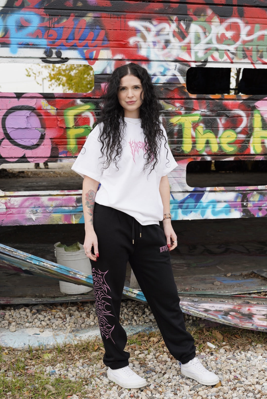 Girl wearing Black cuffed joggers with pink old English style lettering reading “KINSANE” on the right side and pink tribal outlined lettering reading “FOREVER” on the left side 