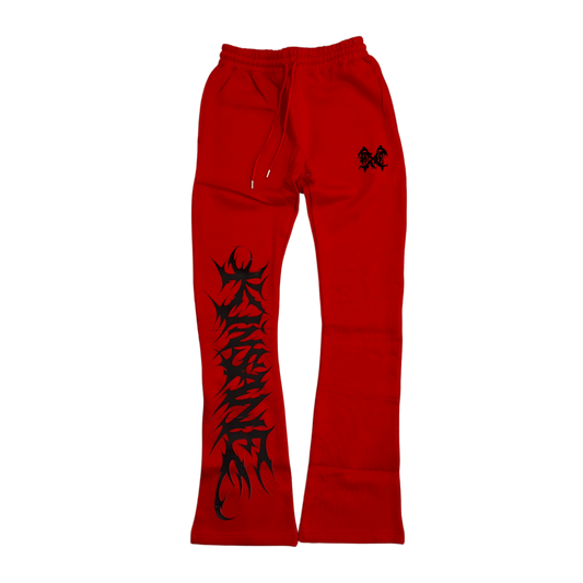 Red stacked sweatpants with black tribal lettering reading “KINSANE” on the left side leg and a black logo on the right side 