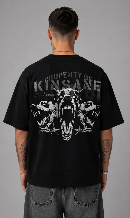 Back view of a man wearing a black t shirt with a white three dogs design and gray text reading “PROPERTY OF KINSANE DIV. 1 TEKKIN MMXXIV” 