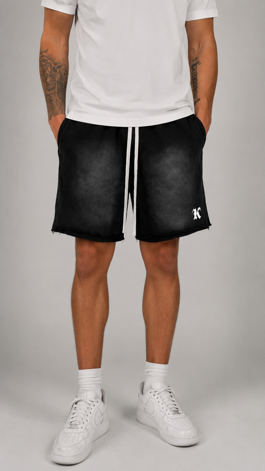 Man wearing Black acid washed shorts with white drawstrings and white “K” logo on the right side 