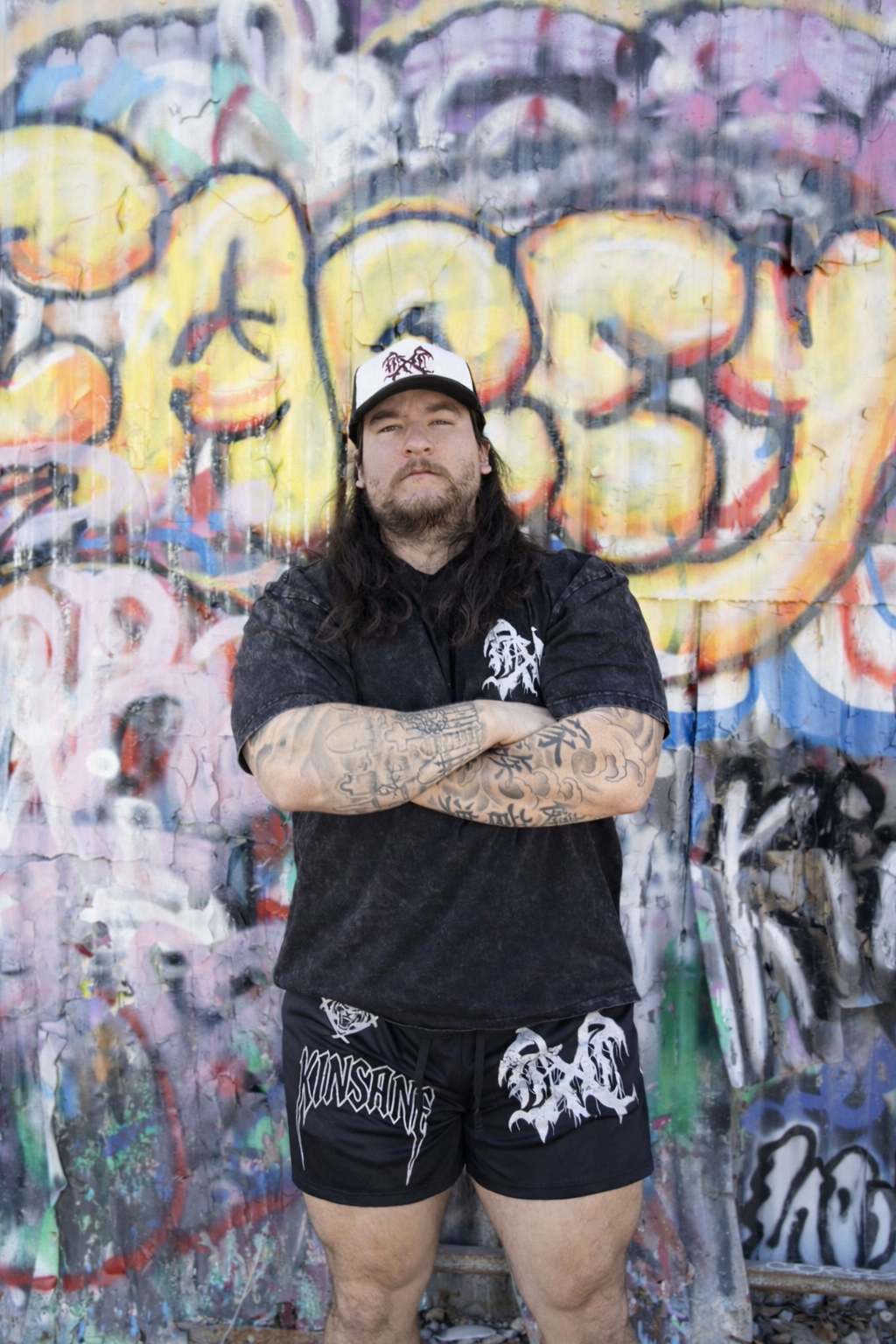 Man wearing Black athletic shorts with black drawstrings and a white tiger logo and white lettering reading “KINSANE” on the right leg and a white logo on the left 