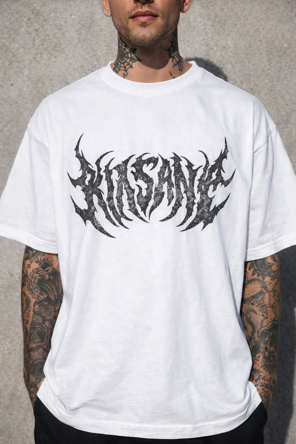Man wearing a white t shirt with dark gray tribal lettering reading “KINSANE” 