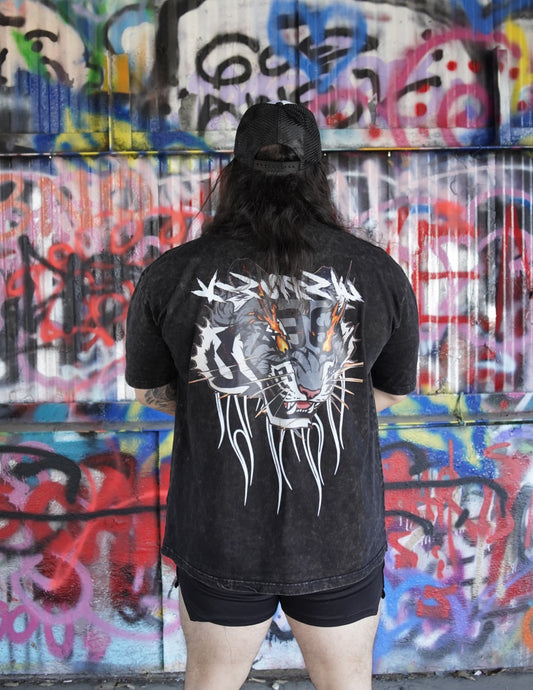 Back view of a man wearing a black acid washed t-shirt with a tiger on fire design and white lettering reading “KINSANE” 
