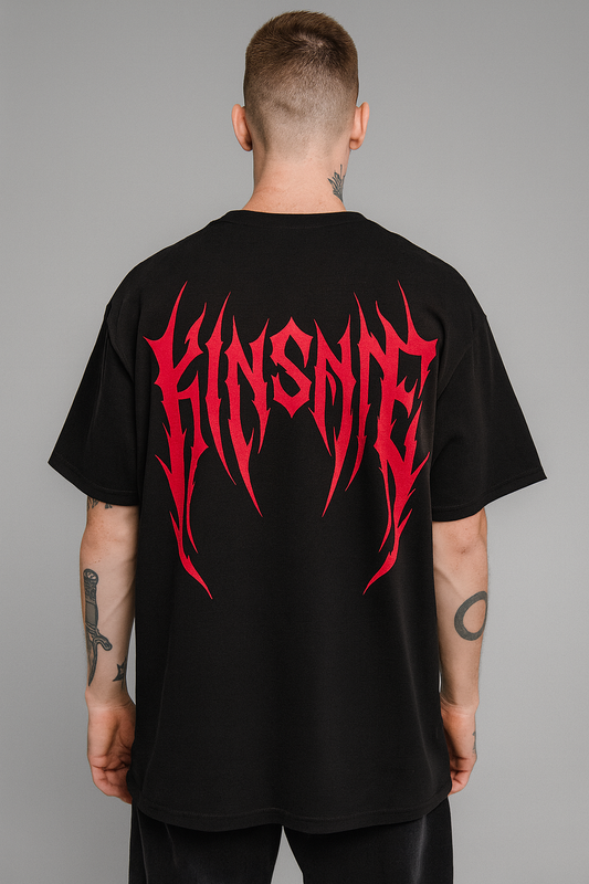 Back view of a man wearing a black T-shirt with red tribal lettering reading “KINSANE” 