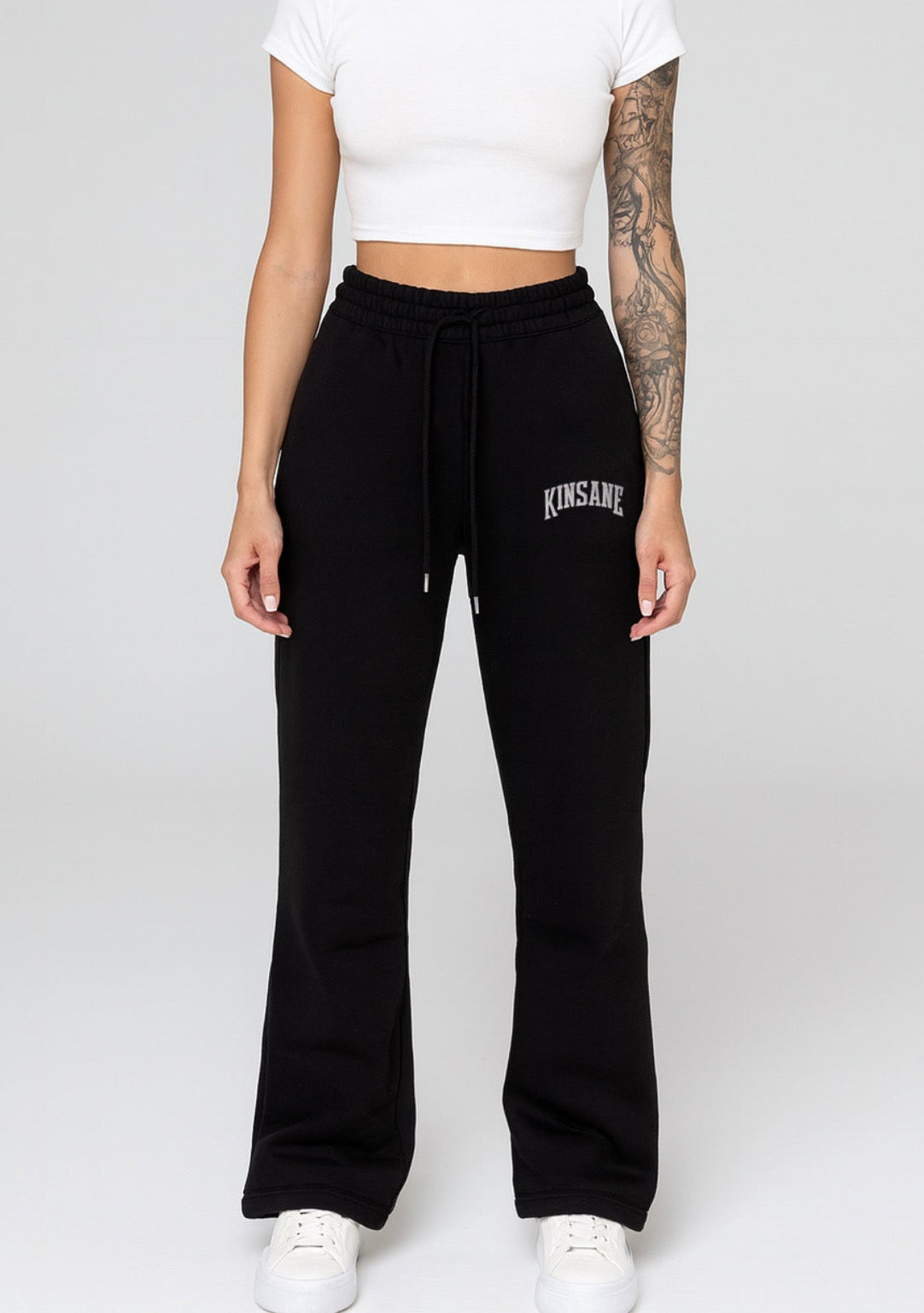 Girl wearing black stacked sweatpants with white lettering reading “KINSANE” on the right side 