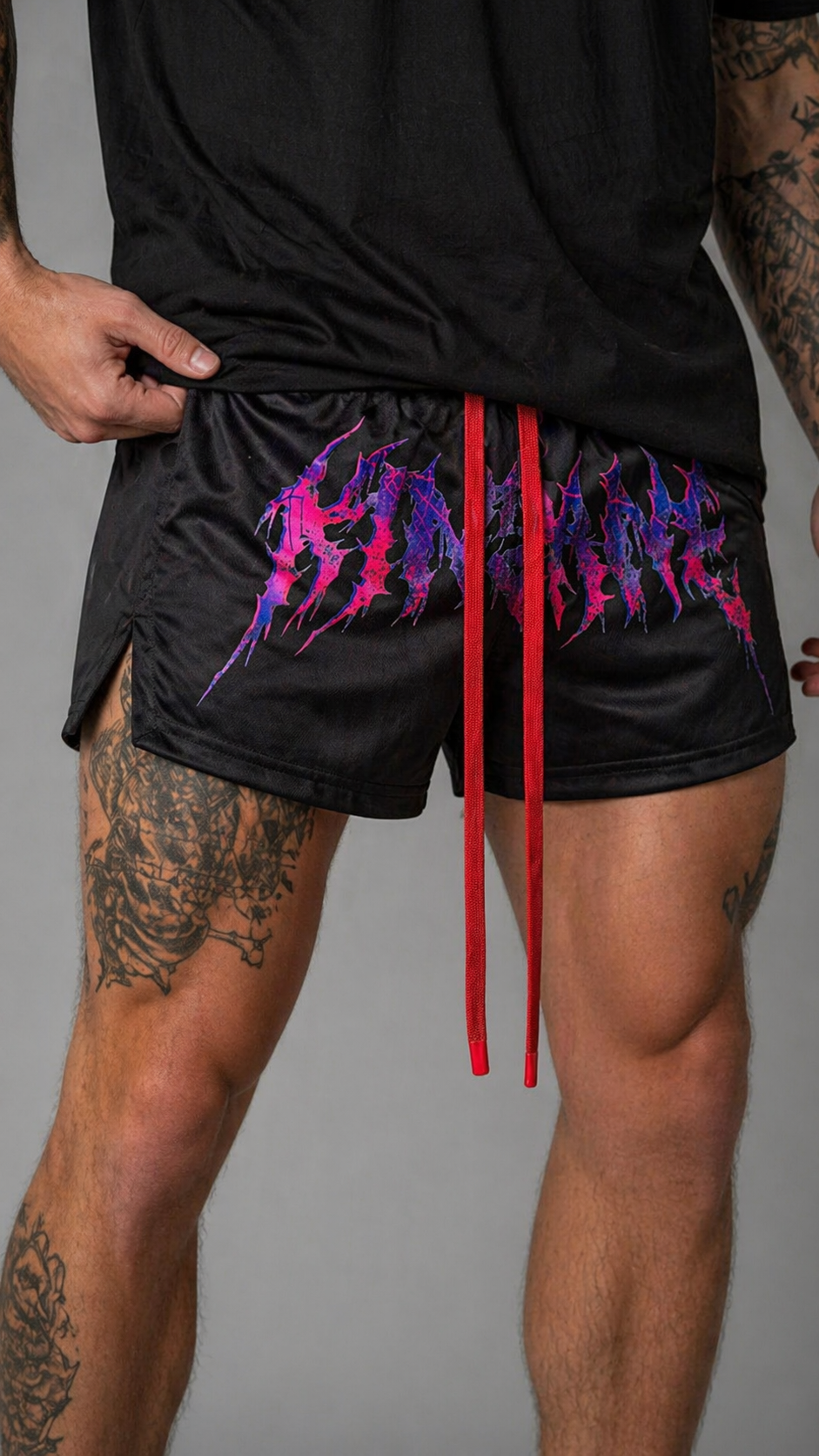 Man wearing Black athletic shorts with elastic waistband and red drawstrings with red and purple tribal lettering reading “KINSANE” across the middle 