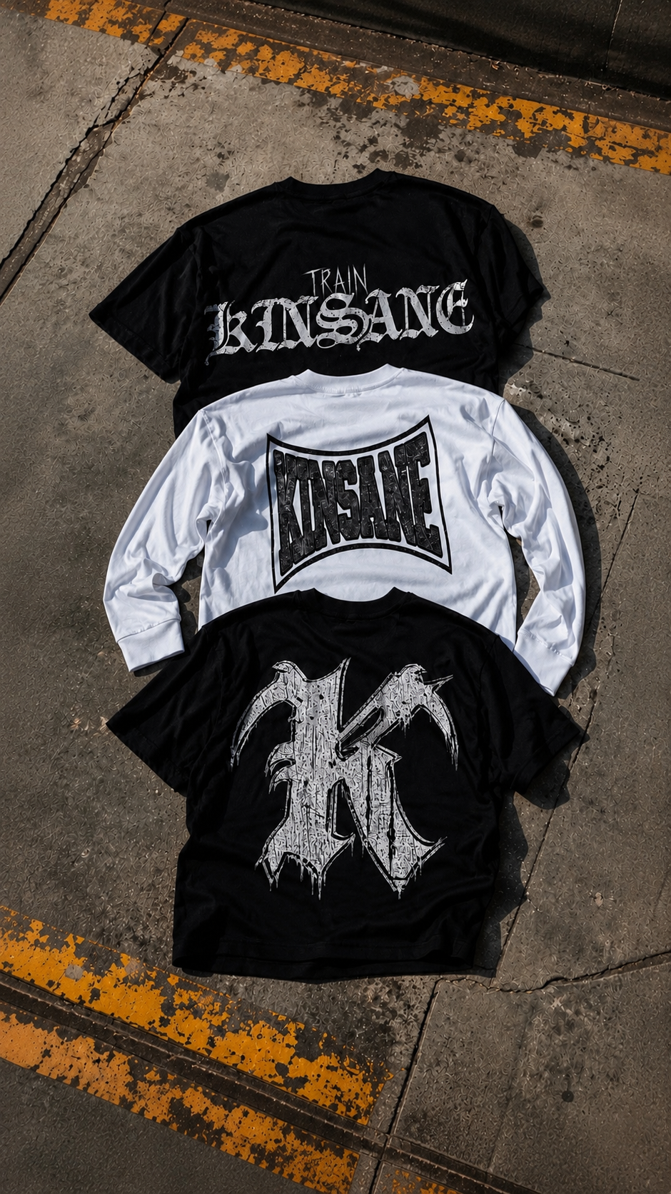 KINSANE graphic apparel collection featuring black and white oversized streetwear shirts with bold gothic graphics photographed on industrial concrete.
