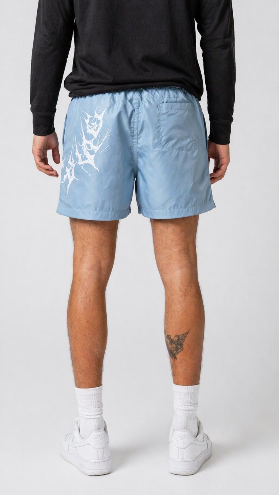 Back view of a man wearing Light blue shorts with light blue drawstrings and white lettering on the left leg reading “KINSANE”