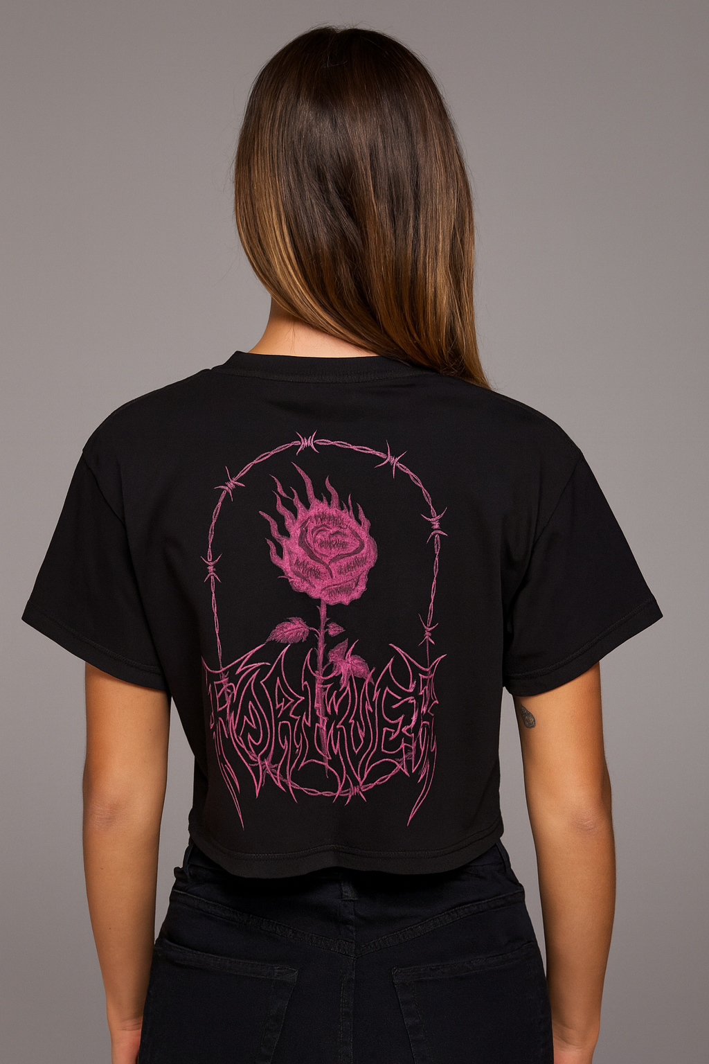 Back view of a girl wearing a black crop top T-shirt with a pink rose and barbed wire surrounding it and pink lettering reading “FOREVER” 
