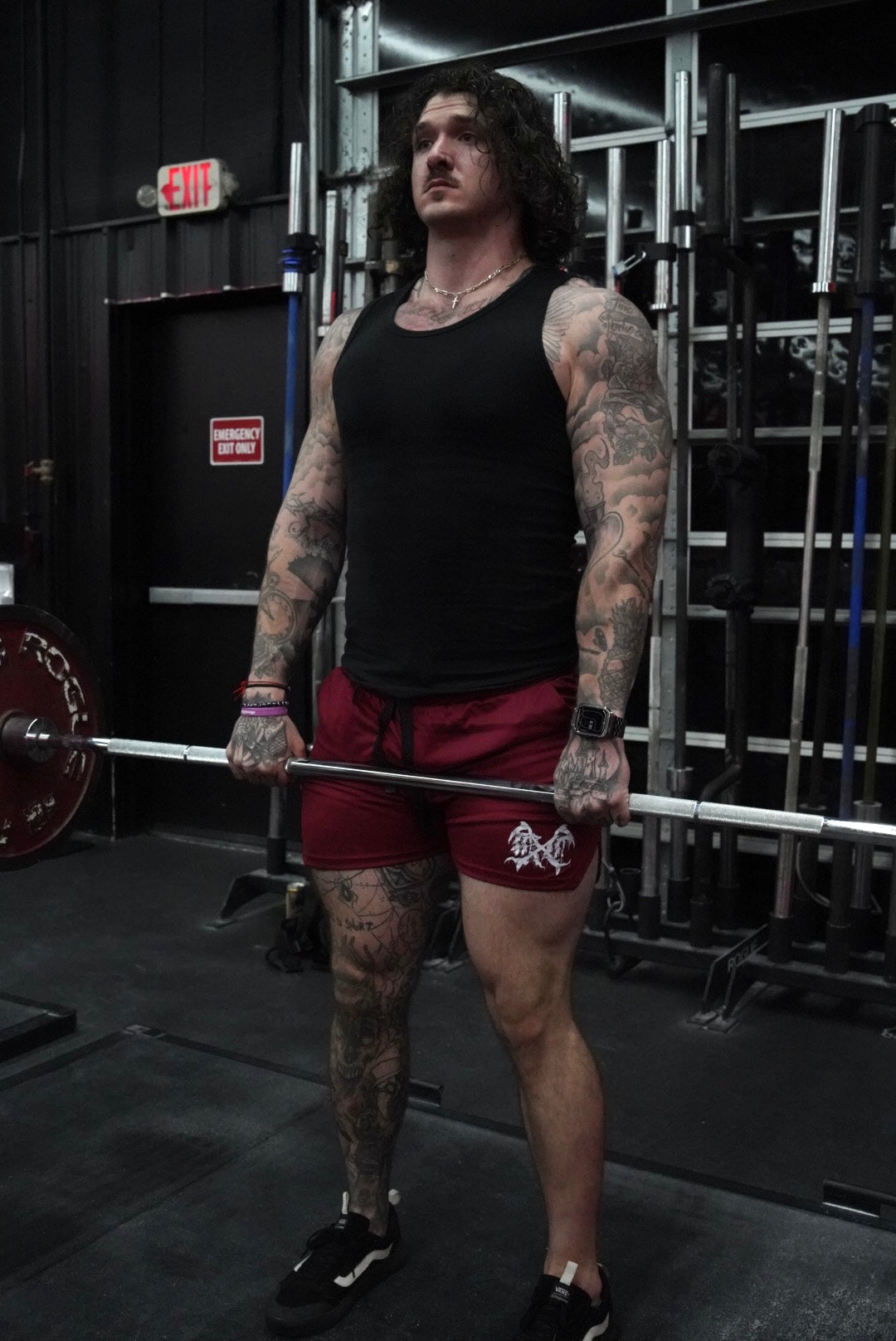 Man lifting weights wearing Maroon athletic shorts with black drawstrings and white logo on the left leg 
