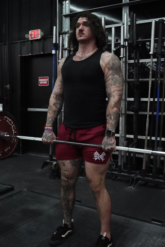 Man lifting weights wearing Maroon athletic shorts with black drawstrings and white logo on the left leg 