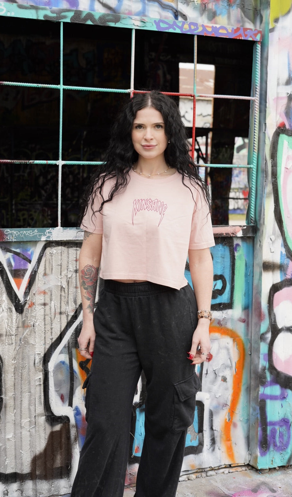 Girl wearing Pink crop top T-shirt with pink outlined lettering reading “KINSANE” 