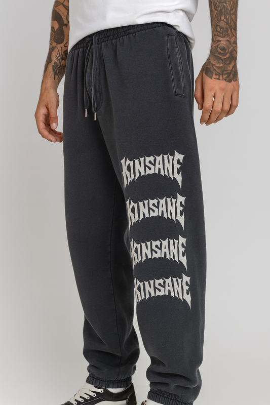 Guy wearing grey cuffed joggers with stacked white lettering reading “KINSANE” four times on the right side 
