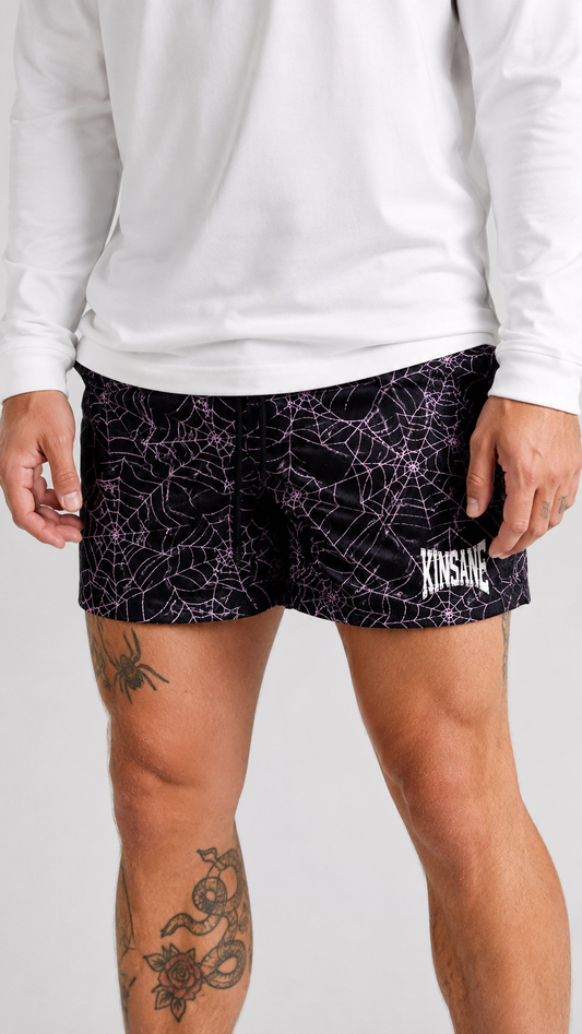 Man wearing Black shorts with pink web design and white text reading “KINSANE” 