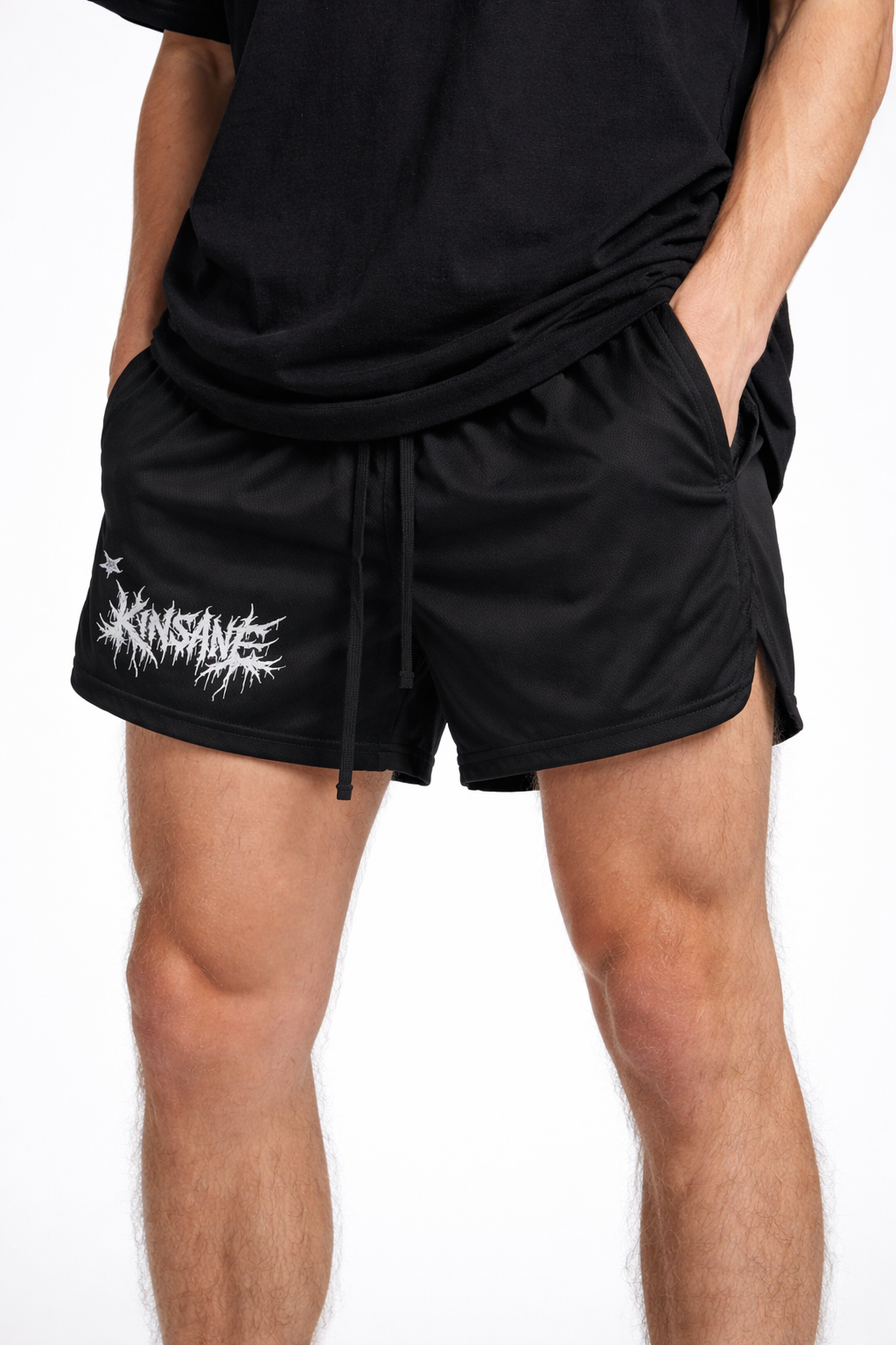 Man wearing Black athletic shorts with black drawstrings and white lettering reading “KINSANE” on the right leg 