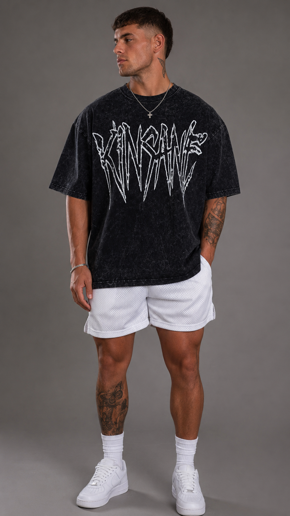 Man wearing Black acid washed t shirt with white outlined text reading “KINSANE” 