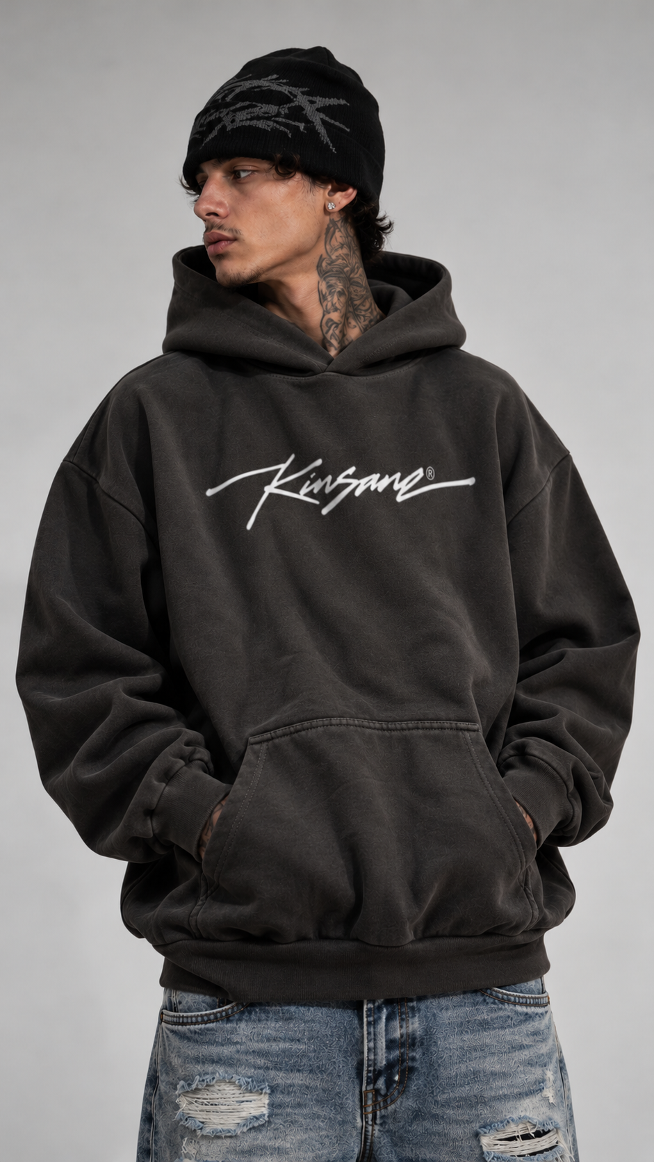 Man wearing Gray hoodie with white cursive text on the front reading “KINSANE®️”
